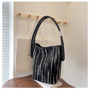 Detail of striped woven tote bag with black leather handle and silver metal hardware