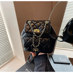 Detail of black quilted leather backpack showing golden chain straps and turn-lock closure