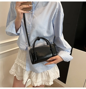 Detail of a chic black rectangular handbag with twin handles and adjustable shoulder strap