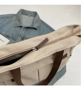 Detail of smooth metal zipper and brown leather puller on a canvas tote bag