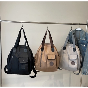Three nylon backpacks in black, khaki, and light grey showing multiple storage pockets