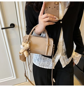 Close-up of beige square crossbody bag with CLEAROK logo and cute plush bear charm