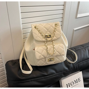 Close-up of quilted cream backpack with gold chain detail and dual turn-lock closures