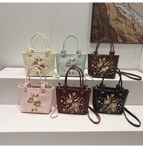 Sacs seaux avec broderies chinoises en six couleurs exposés sur un présentoir blanc
