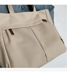 Close-up of beige canvas tote bag with brown leather details and decorative stitching
