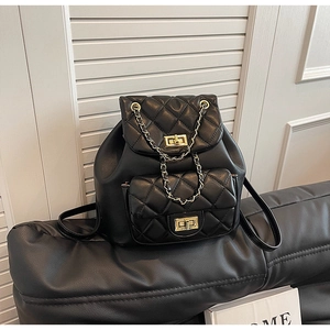 Detailed close-up of quilted black leather backpack with gold chain and twist lock clasp