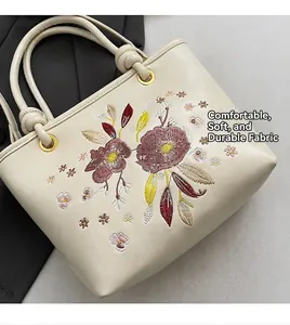 Détail de broderie florale sur sac cabas en similicuir crème avec anneaux dorés