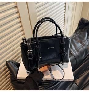 Dettaglio della borsa tote in vernice nera con manici rotondi e logo a rilievo