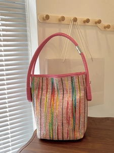 Colorful striped knit bucket bag with pink faux leather handles and silver metal accents