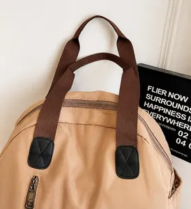 Close-up of durable brown nylon backpack handles with reinforced leather and stitching