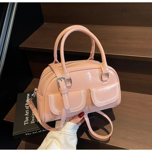 Dettaglio borsa Boston rosa con cerniere argento e tasche anteriori su legno