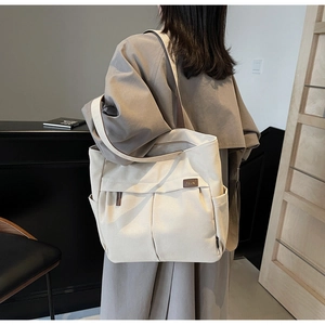 Detail of beige canvas tote bag showing the side pocket and brown leather logo tag