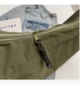 Close-up of smooth zipper with green woven pull cord on army green nylon bag