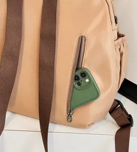Detail view of the side zipper pocket on a beige travel backpack showing phone storage space