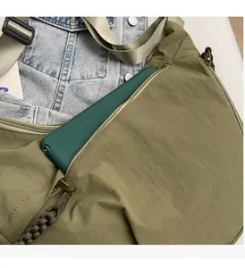 Detail of army green nylon crossbody bag showing spacious front pocket for a tablet