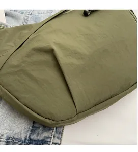 Detail of army green nylon crossbody bag with black zipper closure and textured rope puller