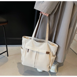 Macro shot of large canvas tote bag with functional pockets and leather logo detail