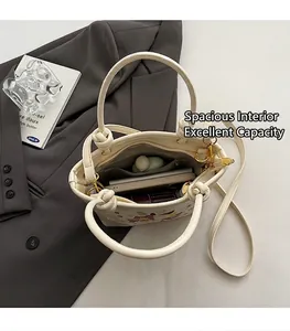 Vue de l'intérieur du sac seau brodé beige avec compartiment spacieux et poche zippée