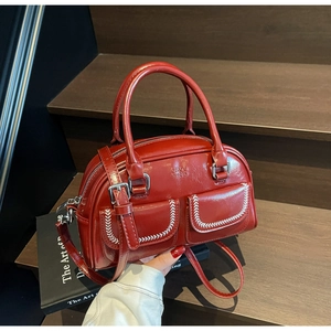 Dettaglio della borsa Boston in pelle verniciata bordeaux con cuciture bianche e logo