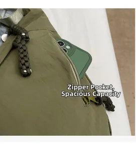 Detail view of the nylon shoulder bag showing side zipper pocket with a green smartphone