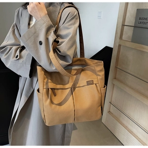 Detail of khaki canvas tote bag showing side pocket and embossed leather logo patch