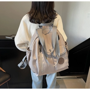 Grey Oxford fabric backpack with multiple zipper pockets shown on a model