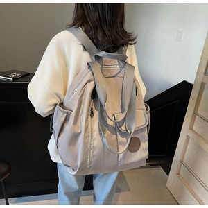 Close-up of lightweight light grey Oxford fabric backpack with multiple storage pockets
