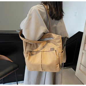 Detail view of khaki canvas tote bag featuring front pockets and premium leather logo tag