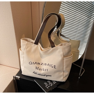 Detail van canvas tote bag met bruine lederen handvatten en zijvak voor opslag