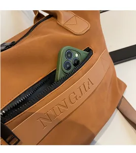 Detail view of brown leather travel bag featuring a side zipper pocket for smartphone storage