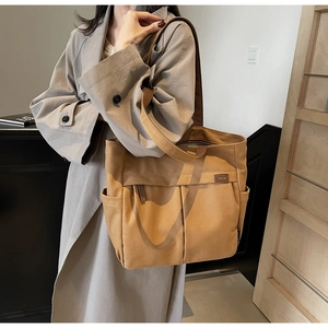 Detail of khaki canvas tote bag featuring dual front pockets and leather TELN logo patch