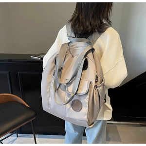 Rear view of a light grey large-capacity Oxford backpack shown on a model in a minimal setting
