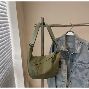 Detail of olive green nylon crescent bag with woven zipper pull on metal stand
