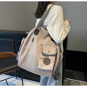 Detail view of beige nylon backpack with adjustable straps and front pocket for travel