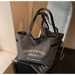 Detailoverzicht van grote grijze canvas tas met zijvak en bruine leren handgrepen