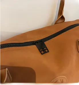 Detail shot of smooth black zipper closure on a durable brown crossbody tote bag