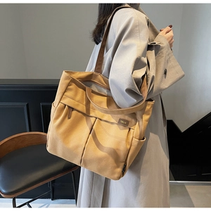 Close-up of khaki canvas tote bag featuring multi-pocket design and TELN logo detail