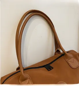 Detail of reinforced round leather handles and premium dual zippers on brown travel bag