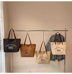 Row of four large canvas tote bags in different colors hanging on a minimal metal rack