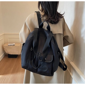 Detailed back view of a black nylon large capacity backpack worn by a female model