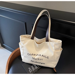 Detail van de gebroken witte canvas shopper met bruine hengsels en handige zijzakken