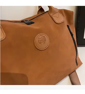 Close-up of the brand logo patch and premium texture on this brown travel duffel bag