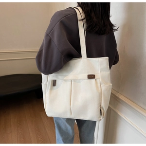 Detailed view of large white canvas tote bag with multiple pockets and shoulder strap