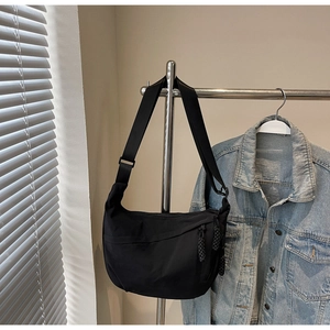 Detail of black nylon crescent crossbody bag with adjustable strap and layered zippers