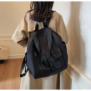 Detail of multi-functional black nylon backpack showing smooth texture and side profile