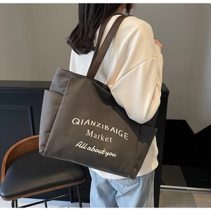Detailopname van de canvas tote bag met zijvak en stijlvolle artistieke belettering