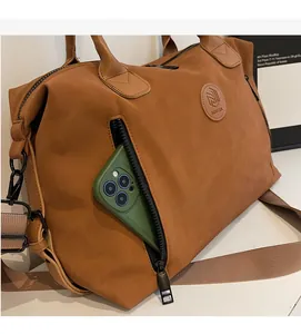 Brown matte tote bag detail showing side zipper pocket with a smartphone inside for storage