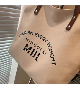 Close-up of beige canvas tote with brown leather handles and reinforced metal rivets