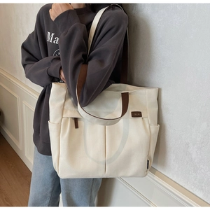 Close-up of cream canvas tote bag with brown straps and side pockets for storage
