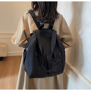 Rear view of model wearing a large black oxford backpack for casual travel and fashion